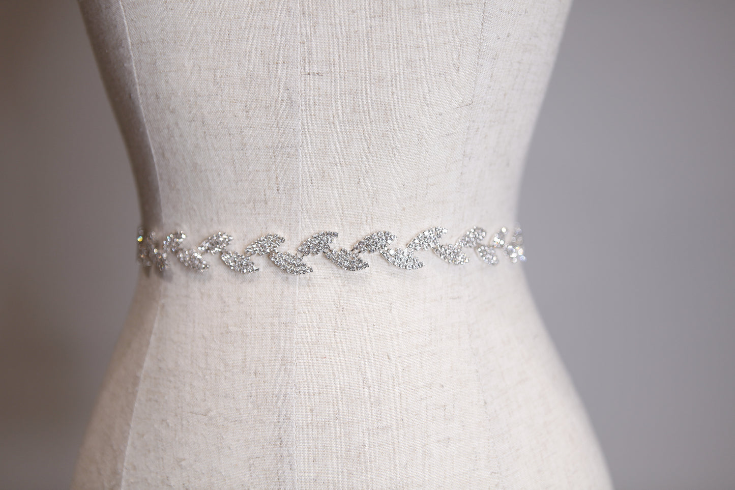 Silver belt with crystals on a mannequin against a neutral background