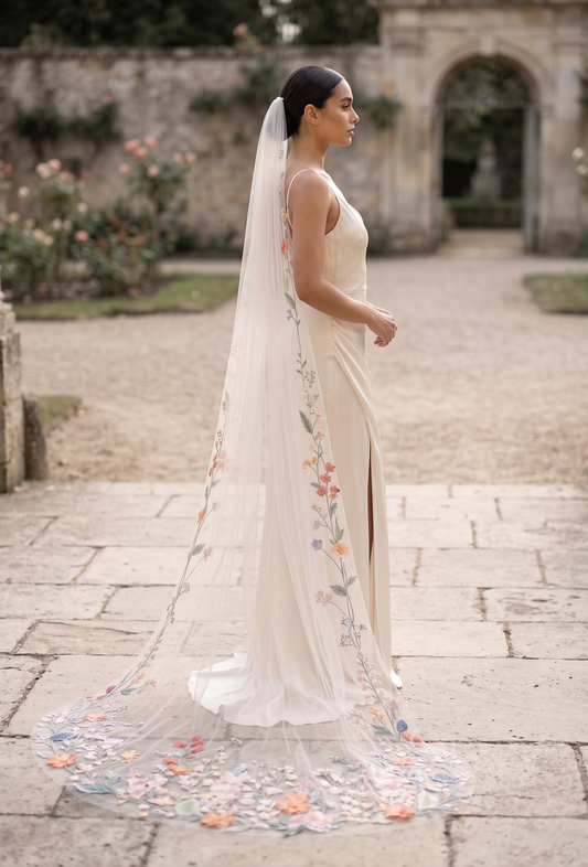 Woman in a floral wedding dress with a long veil in an outdoor setting