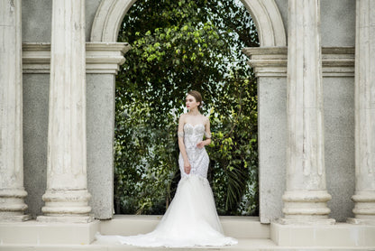 Woman in a wedding dress standing in front of classical architecture with greenery.