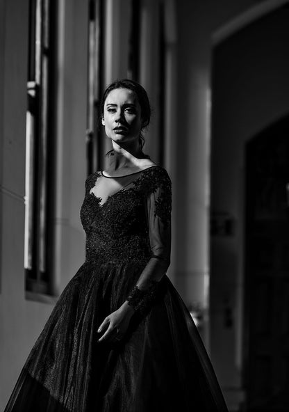 Woman in a black dress standing in a dimly lit room.