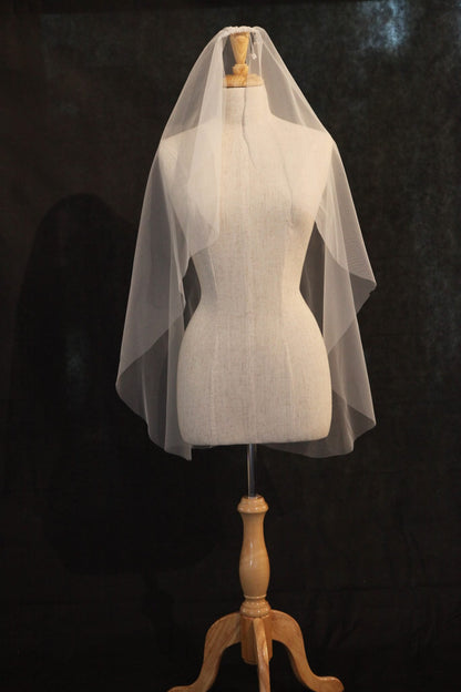 White wedding veil on a wooden mannequin stand against a dark background