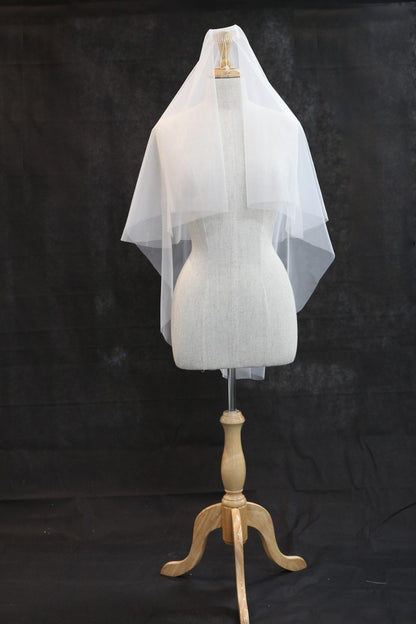 White veil on a wooden mannequin stand against a black background