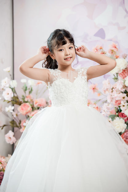 Young girl in a white dress posing in front of floral decorations