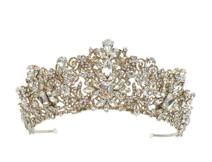 Gold tiara with intricate design and sparkling stones on a white background