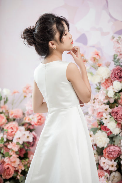 Woman in a white dress standing in front of a floral backdrop