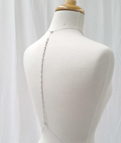 Mannequin wearing a silver chain dress with a white curtain background
