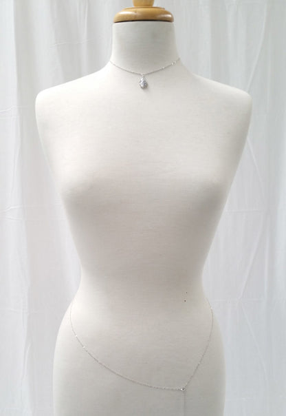 Mannequin wearing a delicate necklace against a white curtain background