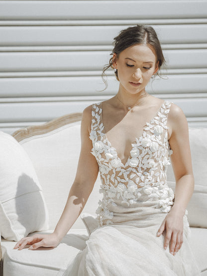 Woman in a white floral dress sitting on a white couch with a light gray background