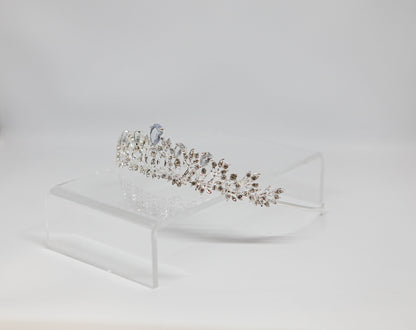 Silver tiara on a clear stand against a light gray background