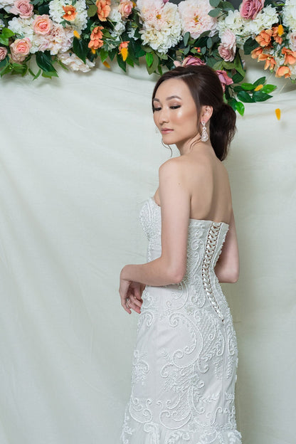 Woman in a white strapless dress with floral decorations in the background