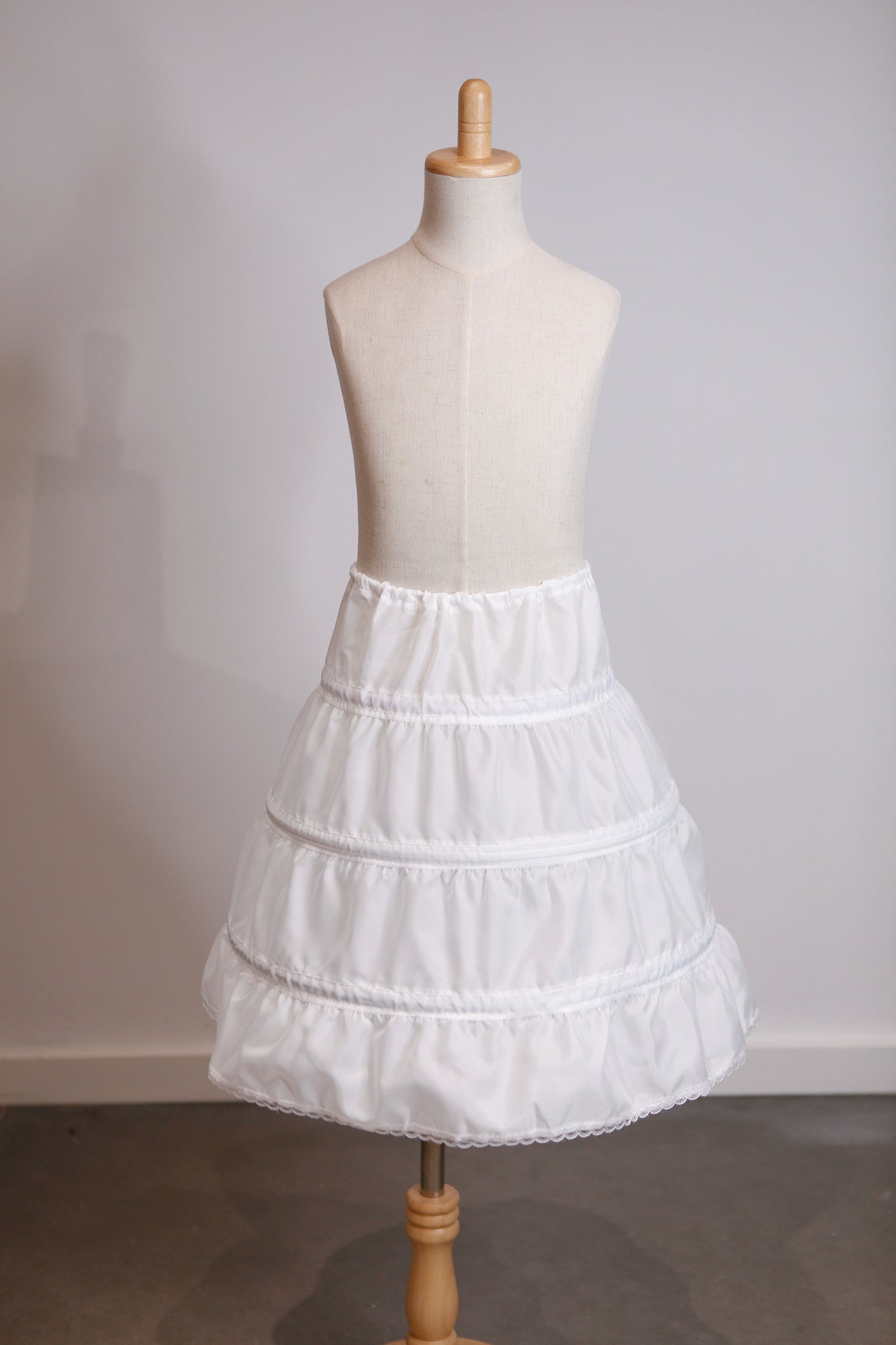 White petticoat on a mannequin against a plain background