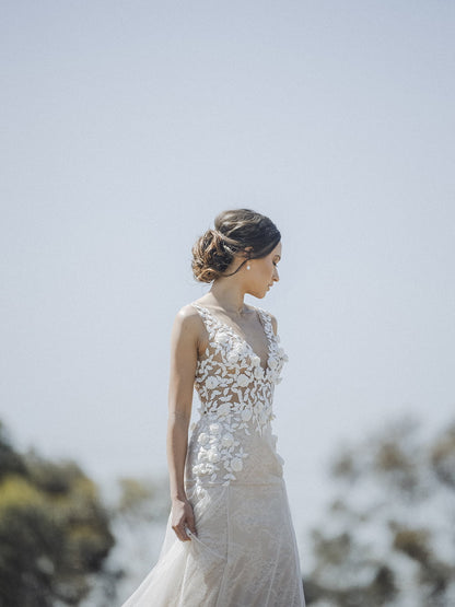 Woman in a white lace dress standing against a blurred natural background