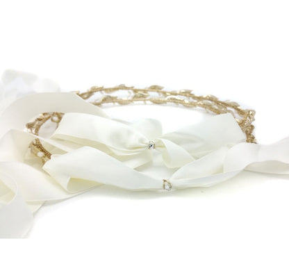 White ribbon with gold chain and pearl accents on a white background