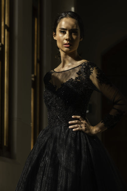 Woman wearing a black lace dress in a dimly lit setting