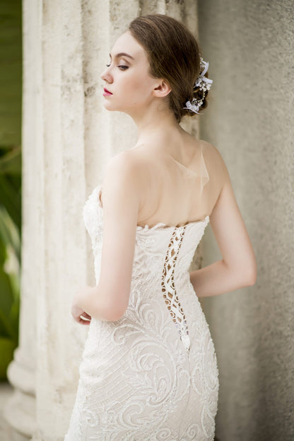 Woman wearing a white lace wedding dress against a classical architecture background