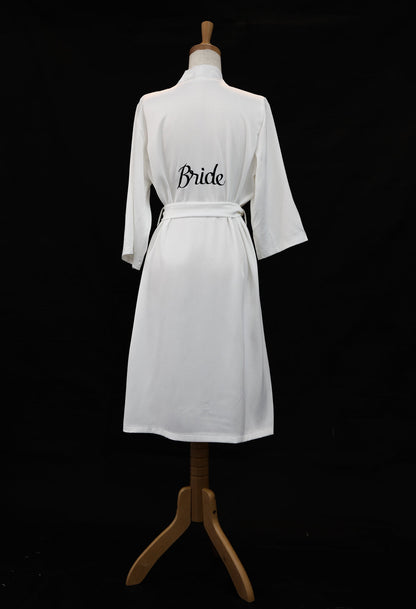 White robe with 'Bride' text on a mannequin against a black background