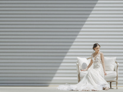Woman in a white wedding dress sitting on a chair against a metallic background