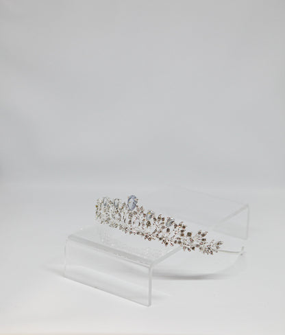 Diamanté tiara on a clear stand against a light gray background