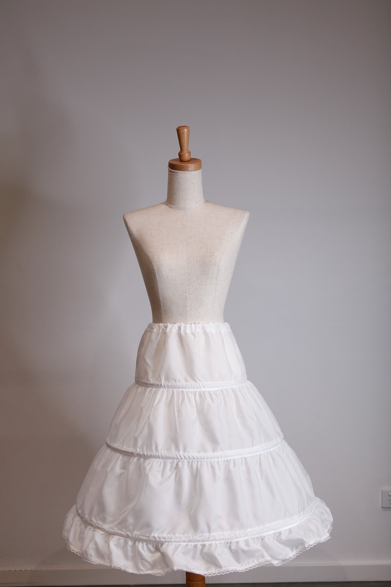White petticoat on a mannequin against a plain background