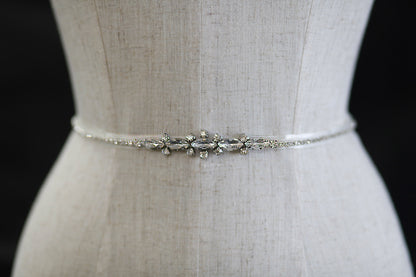 Silver belt with floral design on a mannequin against a black background