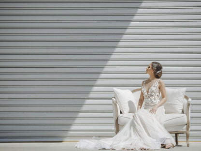Bride in a white wedding dress sitting on a chair with a modern, metallic background