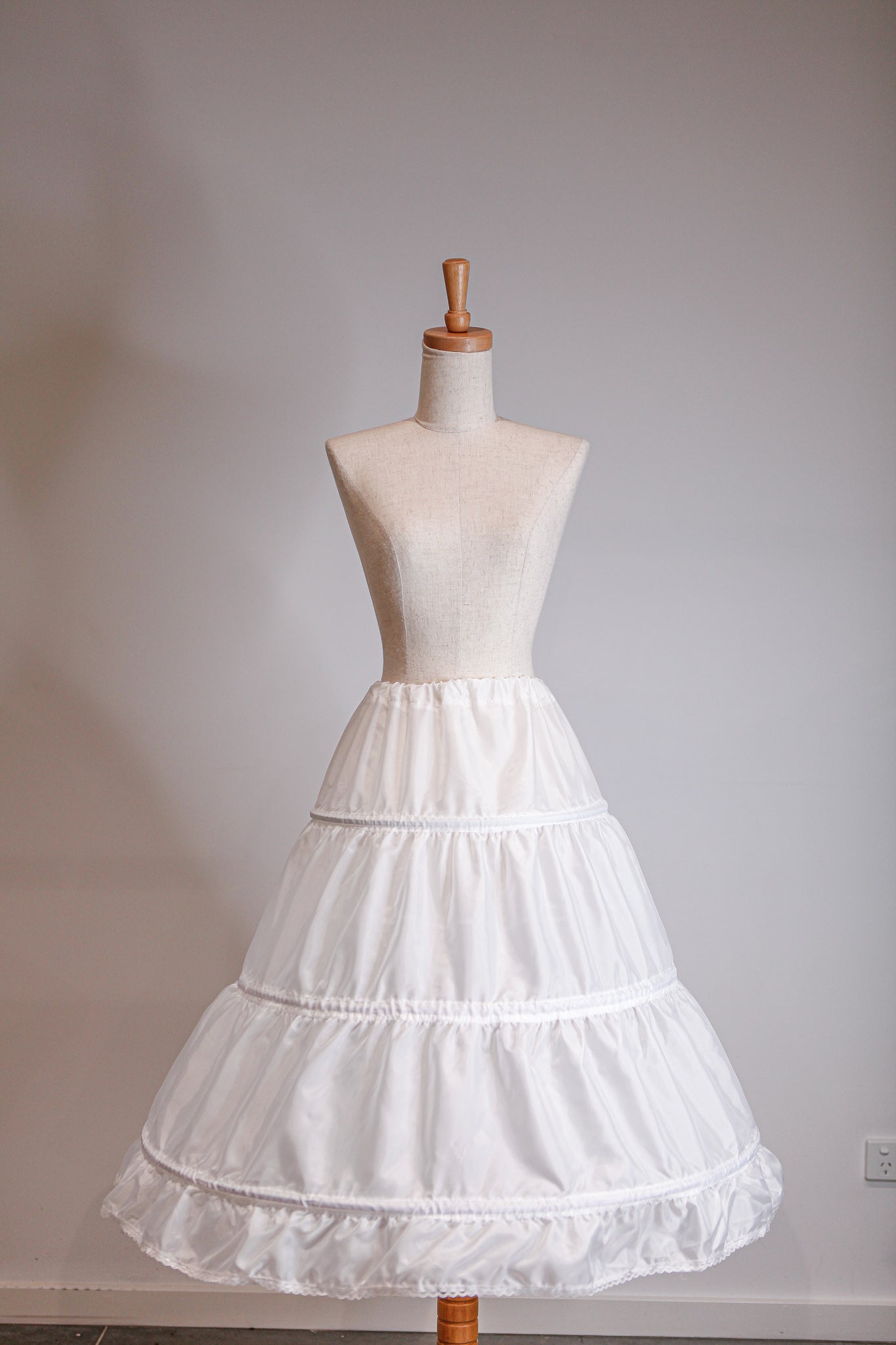 White petticoat on a mannequin against a plain background