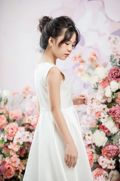 Woman in a white dress standing in front of a floral arrangement