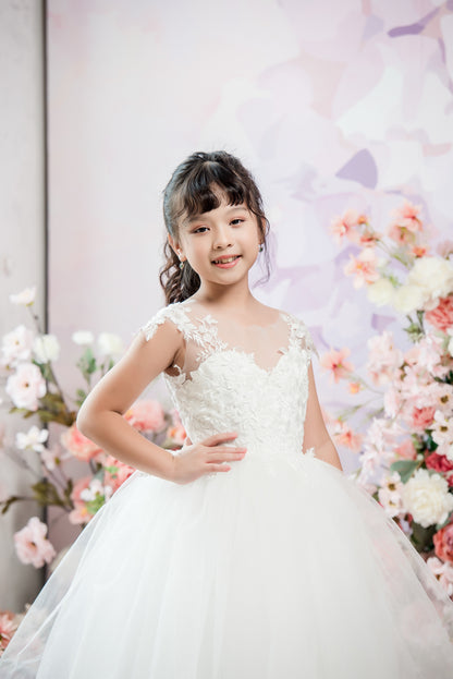 Young girl in a white dress standing in front of floral decorations