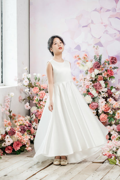 Woman in a white dress standing in front of a floral arrangement