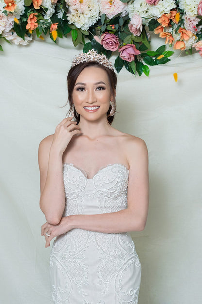 Woman in a white strapless dress with floral decorations in the background