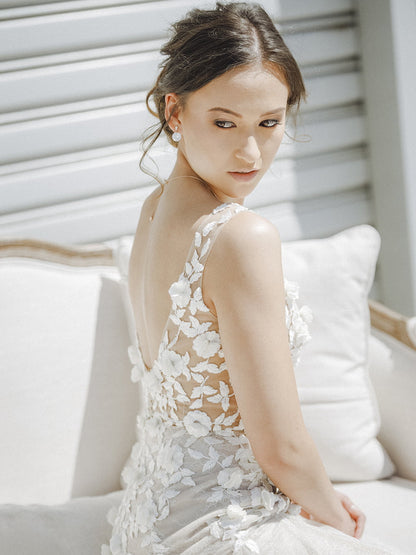 Woman in a white floral dress sitting on a white couch.