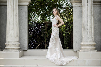 Woman in a white wedding dress standing in front of classical columns with greenery in the background