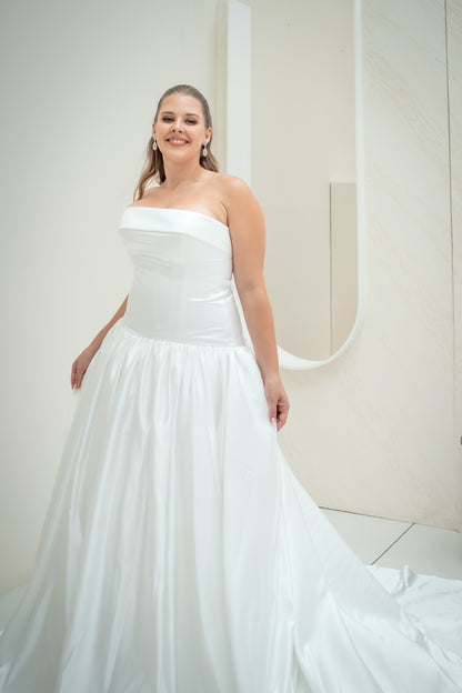 Woman wearing a white strapless wedding dress in a minimal indoor setting