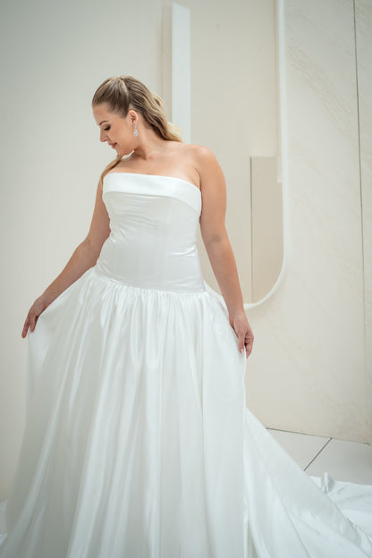 Woman wearing a strapless white wedding dress in a neutral setting