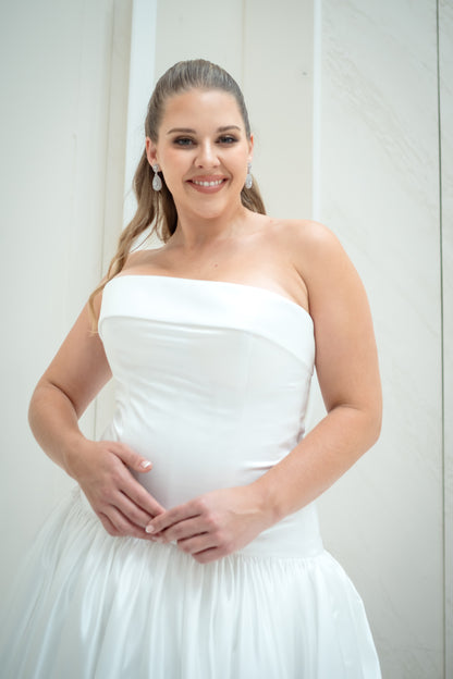 Woman wearing a white strapless dress against a plain background