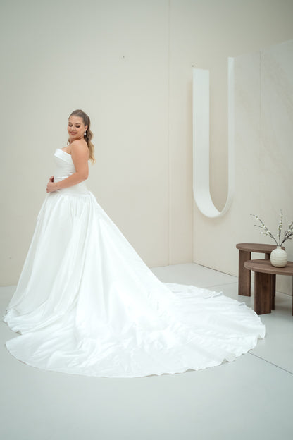 Woman in a white wedding dress standing in a minimalistic room with a neutral color scheme