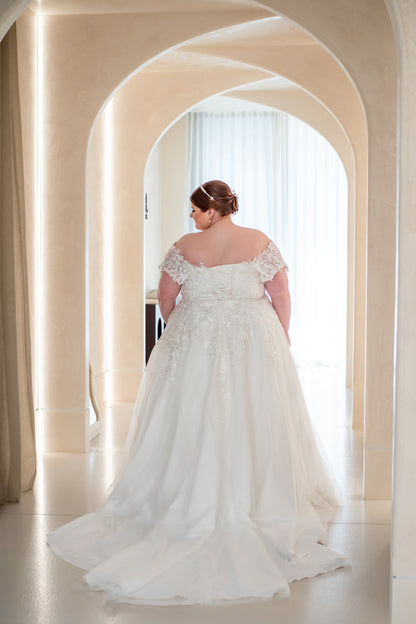 Woman in a white wedding dress standing in an archway with soft lighting