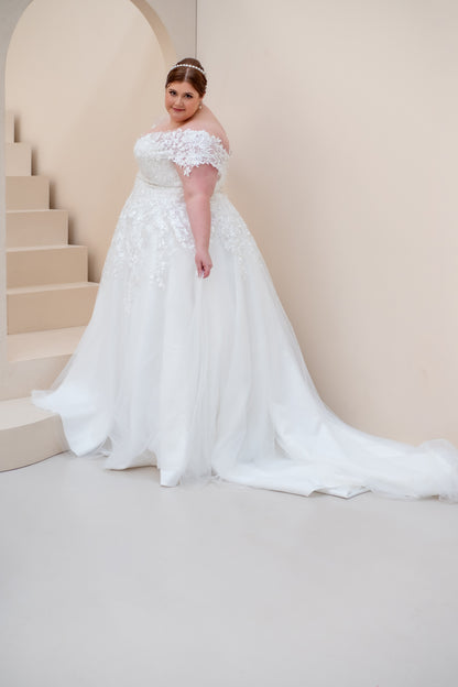 Woman in a white wedding dress standing on a staircase with a neutral background