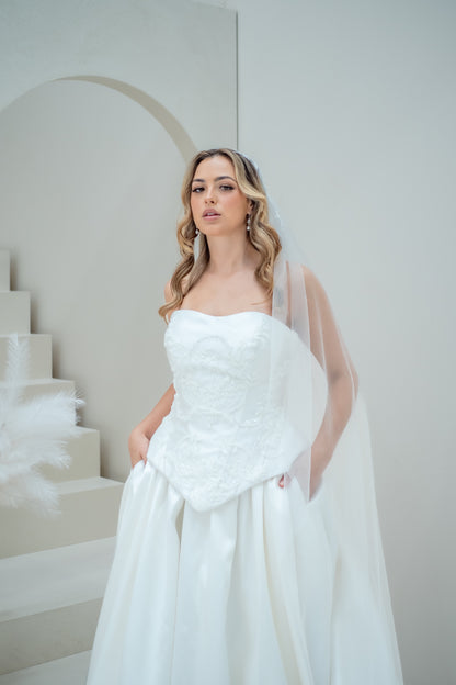 Woman in a white wedding dress standing in a minimalistic setting with a staircase