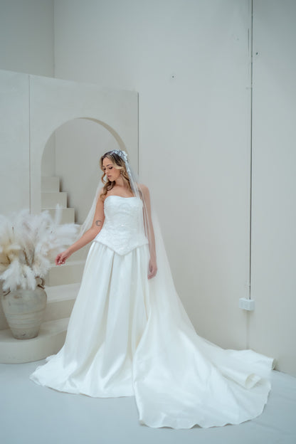 Woman in a white wedding dress standing in a minimalistic room with white walls and decor