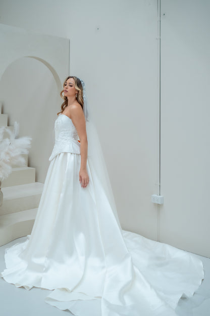 Woman in a white wedding dress standing in a minimalistic room with white walls and floor