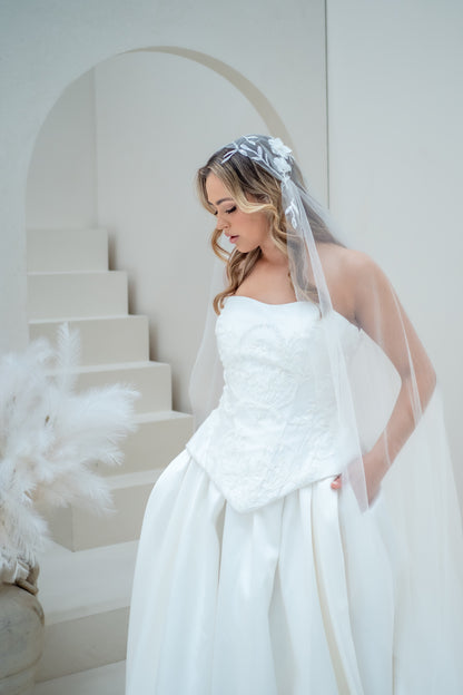 Bride in a white wedding dress with a veil standing in a minimalistic setting