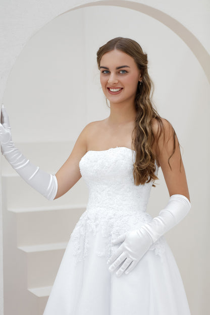 Woman wearing a white strapless dress and long gloves in a bright setting