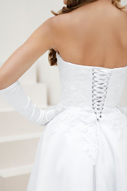 White wedding dress with lace-up back and long gloves on a neutral background