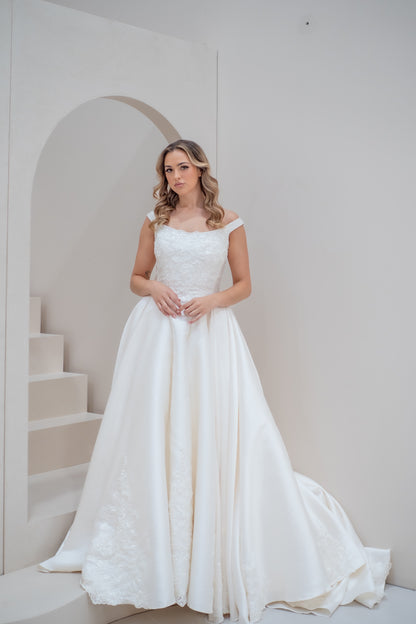 Woman in a white wedding dress standing in a minimalistic room with white walls and stairs
