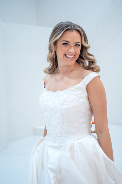 Woman wearing a white wedding dress against a plain background