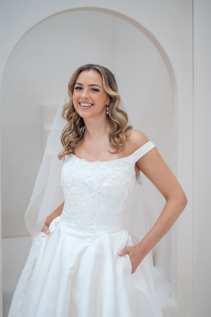Woman in a white wedding dress standing in front of a white archway