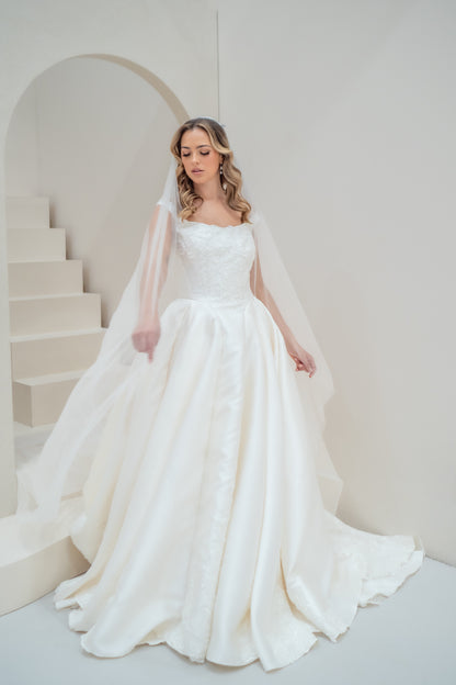 Woman in a white wedding dress with a veil standing in a minimalistic setting