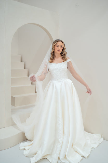 Woman in a white wedding dress standing in a minimalistic room with a staircase