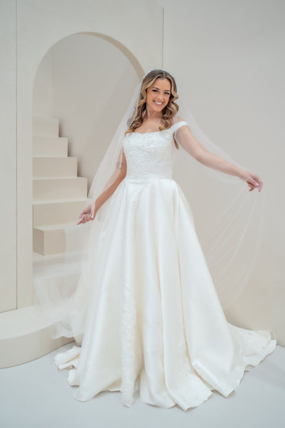 Woman in a white wedding dress standing in a minimalistic room with a staircase